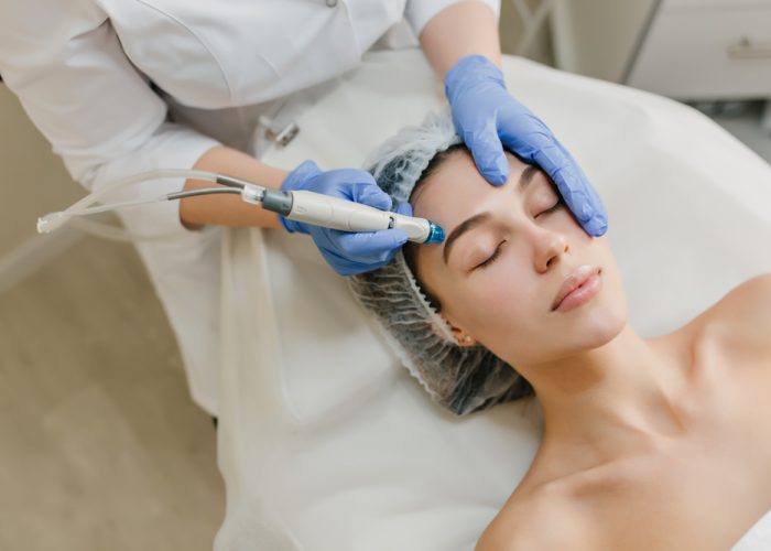 View from above rejuvenation of beautiful woman enjoying cosmetology procedures in beauty salon. Dermatology, hands in blue glows, healthcare, therapy, botox